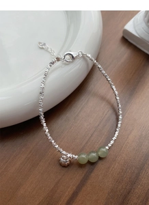 Macro detail of S925 sterling silver crushed beads bracelet with jade and lotus charm