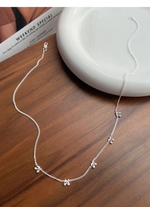 Macro shot of silver cherry pendant necklace with lobster clasp on a ceramic plate