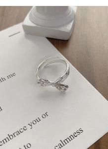 Macro detail of S925 sterling silver bow ring with brushed texture on a white card