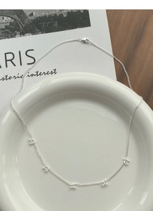 Detail view of S925 sterling silver necklace with five cherry pendants on a ceramic plate