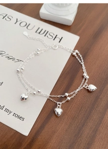 Detail of S925 sterling silver double-layer bracelet with polished heart charms and beads