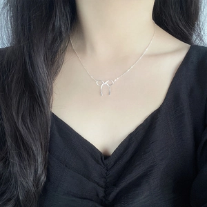 Elegant S925 sterling silver bow pendant necklace worn on a model with a black V-neck top