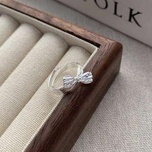 Minimalist S925 sterling silver bow ring with realistic folds on a jewelry tray