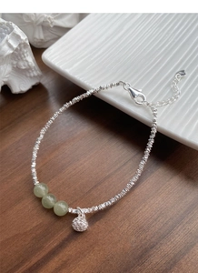 Close-up of S925 sterling silver lotus pod bracelet with green jade beads on a tray