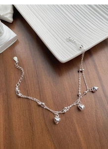 Detailed macro view of S925 sterling silver double-layer bracelet with heart pendants