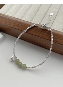 Detail of S925 silver bracelet with green jade beads and a lotus seed pod charm