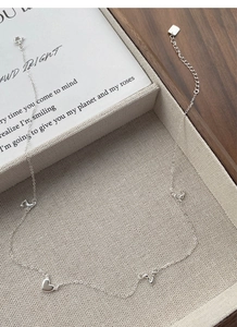 Detailed macro view of S925 sterling silver heart and musical note pendants on a fine chain
