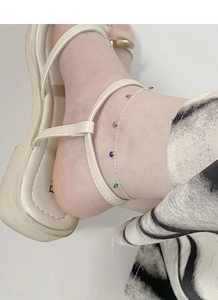Détail d'une chevillère en argent avec des pendentifs colorés portée à la cheville