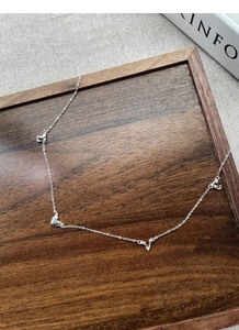 Macro shot of silver S925 necklace with heart and LOVE charms on a wooden tray