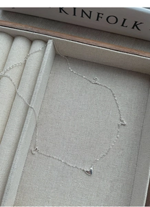 Detail of silver S925 necklace with heart and letter charms in a wooden jewelry box