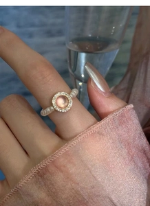 Close-up of pearl beaded ring with pink cat eye stone and zircon accents on a finger