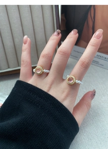 Detail of elegant gold rings with pink faceted stone and white pearl elastic bands