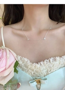 Detail of S925 sterling silver necklace with heart charms worn on a woman neck