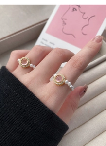 Close-up of pearl bead ring featuring a pink gemstone centerpiece and gold accents