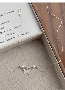Detailed macro view of S925 silver butterfly pendant with elegant pearls on a snake chain