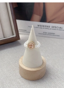 Detail of S925 silver pearl ring with pink gemstone on a white jewelry stand