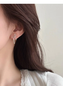 Primo piano di eleganti orecchini a lobo a fiocco in argento S925 per un look delicato