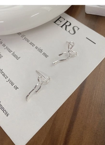 Primo piano di eleganti orecchini a fiocco in argento sterling S925 su sfondo neutro