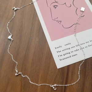 Elegant S925 sterling silver necklace with heart and letter pendants on a wooden surface