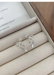 Dettaglio degli orecchini a fiocco in argento S925 su un vassoio portagioie beige