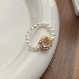 Elegant S925 silver stretch ring with white pearls and a pink gemstone in gold setting