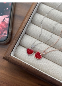 Gros plan de colliers cœur cannelé rouge en argent et or rose dans une boîte à bijoux