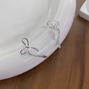 Eleganti orecchini a fiocco in argento sterling S925 presentati su un piatto in ceramica bianca