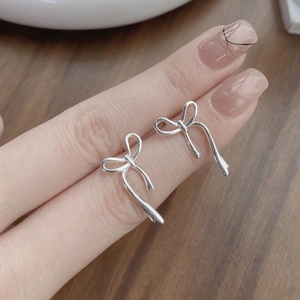 Orecchini a perno a fiocco in argento sterling S925 tenuti a mano su sfondo legno scuro