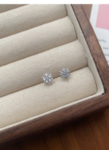 Macro view of flower-shaped silver stud earrings with sparkling diamonds in a jewelry box