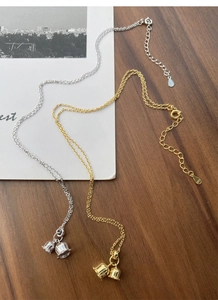 Detailed macro view of S925 silver and gold lily valley bell pendants on fine chains