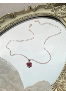 Détail du collier pendentif coeur rouge sur miroir vintage avec dentelle blanche