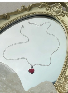 Détail du collier en argent 925 avec pendentif cœur rouge sur un miroir vintage