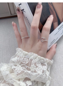 Close-up of S925 silver hollow heart-shaped open rings layered with lace sleeve