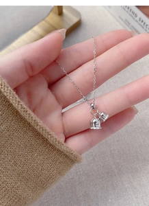 Macro detail of hand-held S925 sterling silver lily of the valley bell pendant necklace