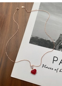 Détail macro d'un pendentif cœur rouge sur collier en argent S925 doré rose avec zircon