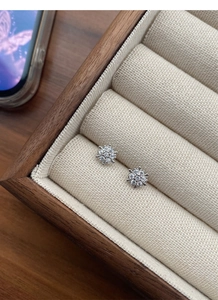 Macro shot of silver S925 flower stud earrings with pavé zircons in a wooden jewelry box