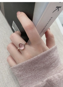Close-up of a pink oval cabochon ring on a finger with soft aesthetic atmosphere