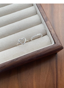 Close-up of S925 sterling silver hollow heart rings on a textured linen jewelry tray