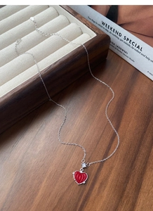 Vue macro détaillée du collier cœur en argent S925 avec pendentif rouge sur boîte en bois
