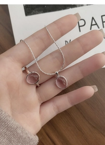 Close-up of a silver jewelry set featuring oval pink gemstones on a necklace and ring
