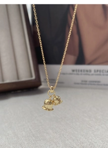 Detail of gold lily of the valley double pendants necklace hanging on a branded card