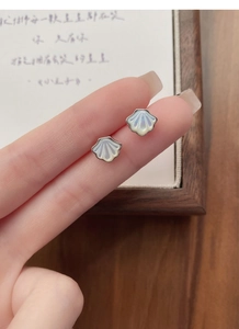 Detailed macro shot of shell-shaped S925 sterling silver studs with iridescent mother of pearl