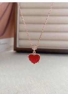 Macro d'un collier cœur en argent S925 avec pierre rouge et chaîne en or rose