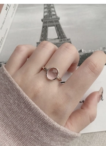 Detail of pink oval stone ring in silver setting worn by model in a romantic setup