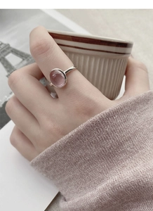 Close-up of S925 sterling silver ring with oval pink gemstone worn on finger