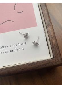 Macro shot of silver flower earrings with white zircons set on a decorative card