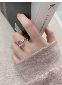 Detail of S925 sterling silver ring featuring a pink oval gemstone on a hand with knitwear