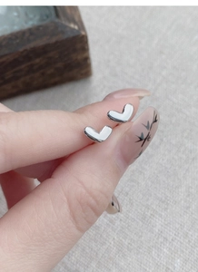Close-up of minimalist S925 sterling silver heart studs held to show small size