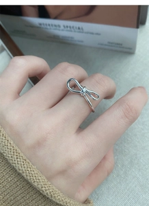 Detail of S925 sterling silver bow ring with adjustable open band on finger