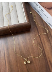 Detailed shot of S925 silver lily of the valley bell pendant with gold O-chain on wood